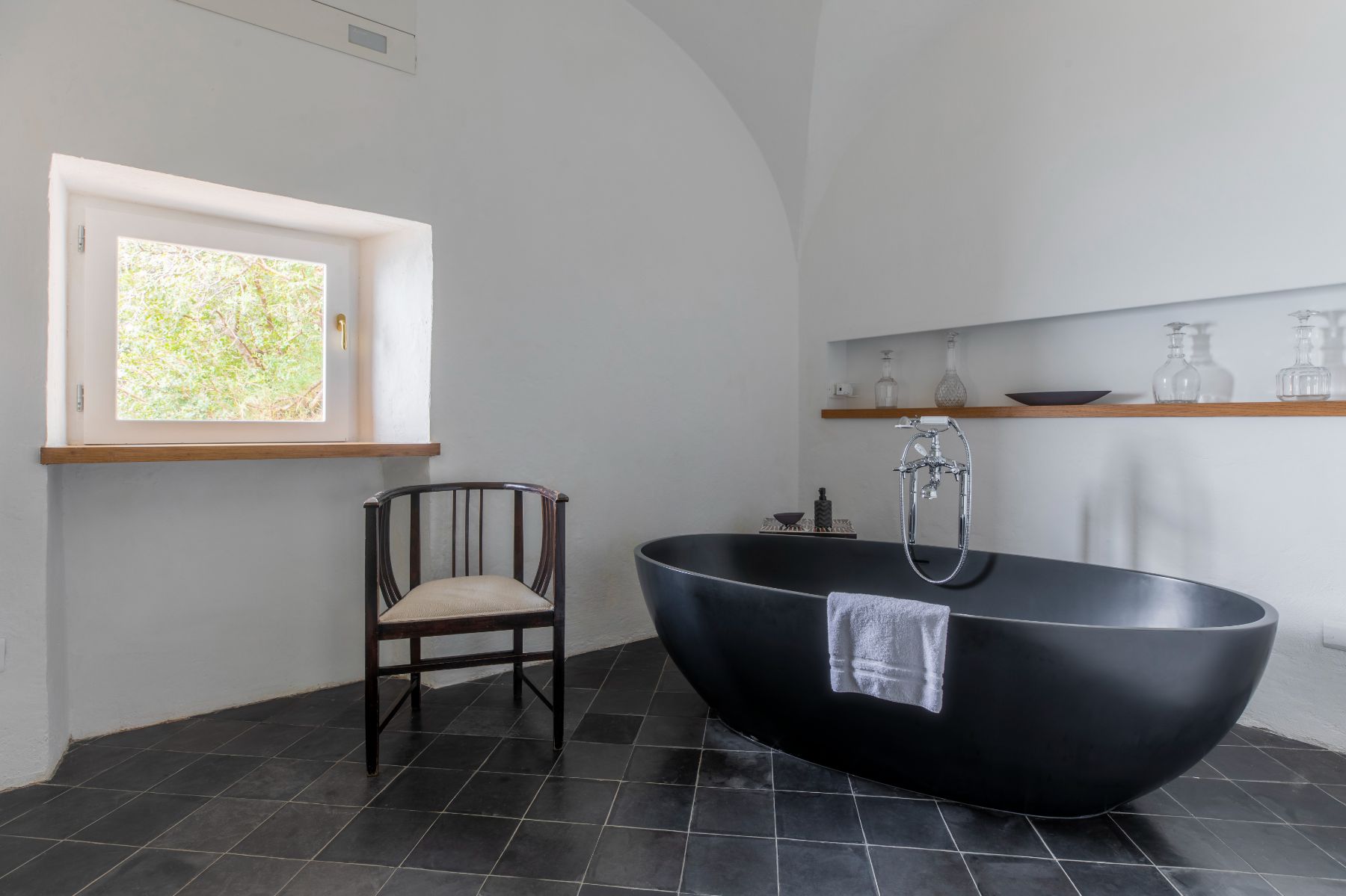 bathroom with black bath tub and chair in villa Il Marinaio, Amalfi