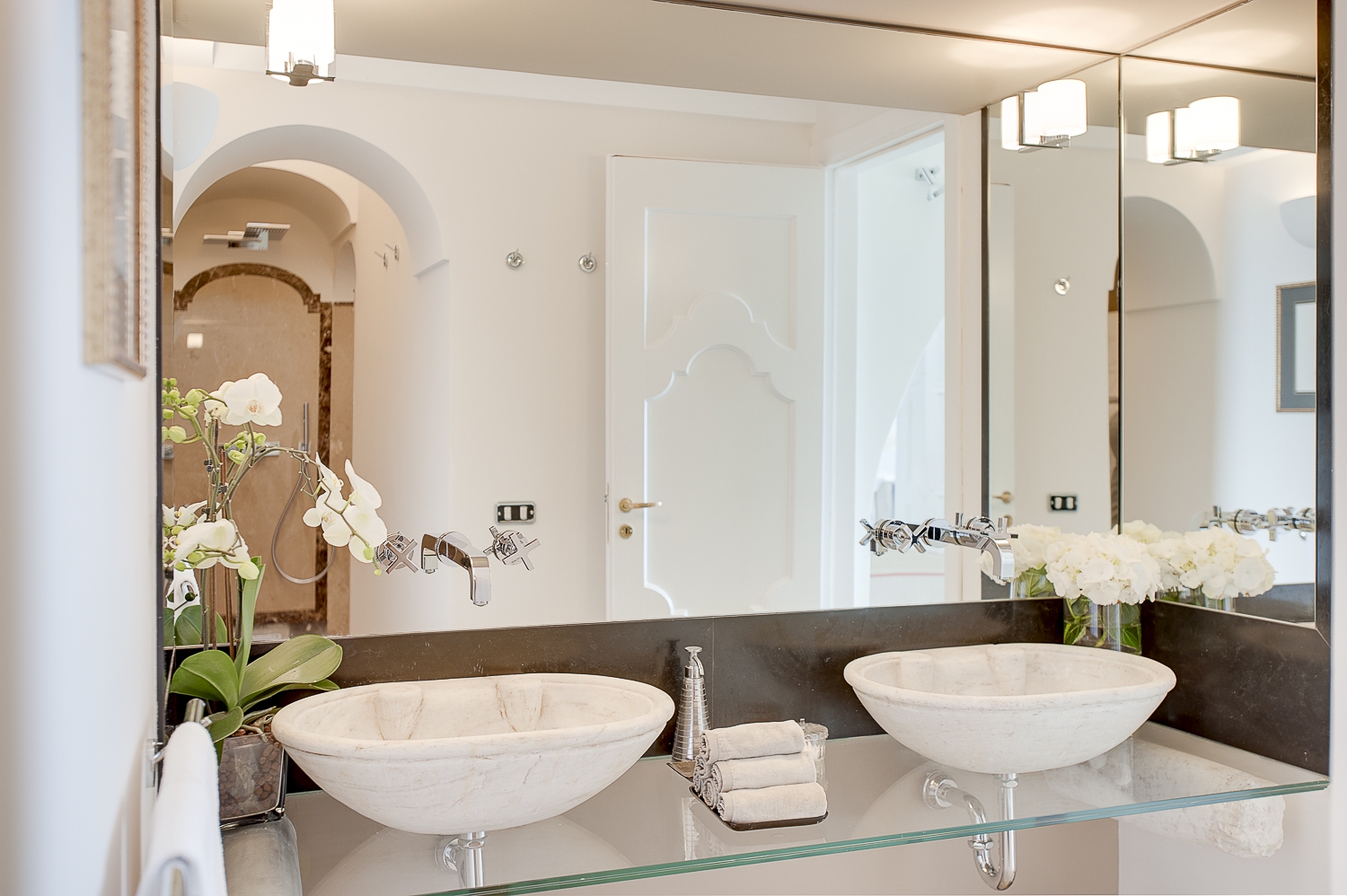 Bathroom with double sinks, shower, flowers and large mirror at Villa di Praiano on the Amalfi Coast in Italy