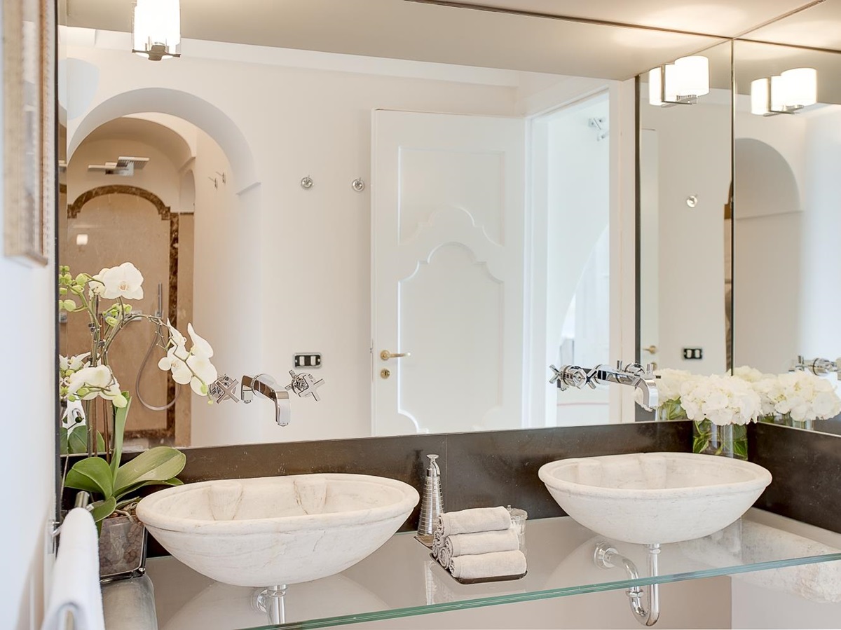 Bathroom with double sinks, shower, flowers and large mirror at Villa di Praiano on the Amalfi Coast in Italy
