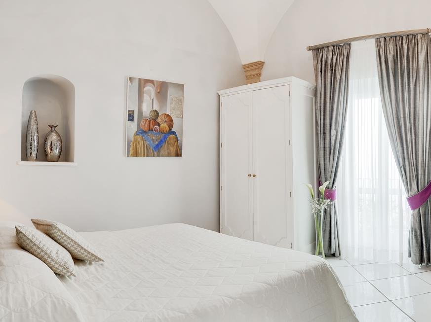 Bedroom with double bed, lamp, desk, chair, paintings, TV and wardrobe at Villa di Praiano on the Amalfi Coast in Italy