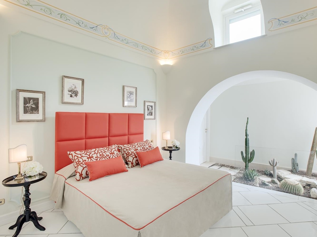 Bedroom with double bed, bedside tables, lamps, picture frames and cacti at Villa di Praiano on the Amalfi Coast in Italy