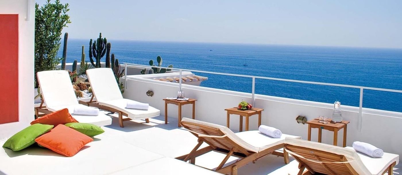 Balcony with sun loungers, tables, cacti and sea view at Villa di Praiano on the Amalfi Coast, Italy