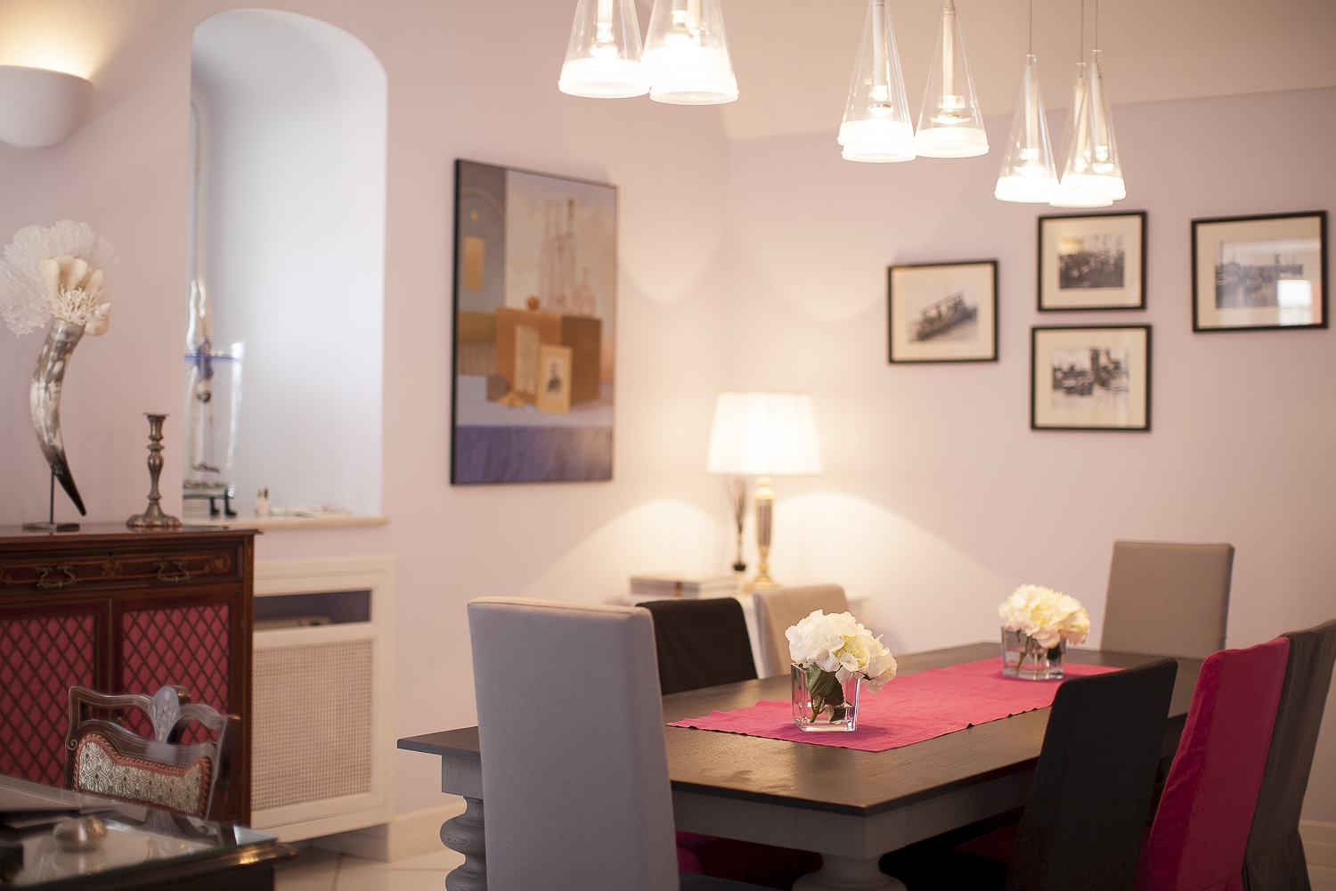 Dining room with table, chairs, hanging lights, picture frames and cabinet at Villa di Praiano on the Amalfi Coast in Italy