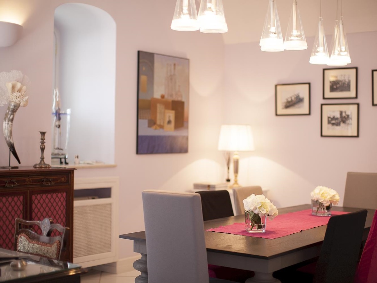 Dining room with table, chairs, hanging lights, picture frames and cabinet at Villa di Praiano on the Amalfi Coast in Italy