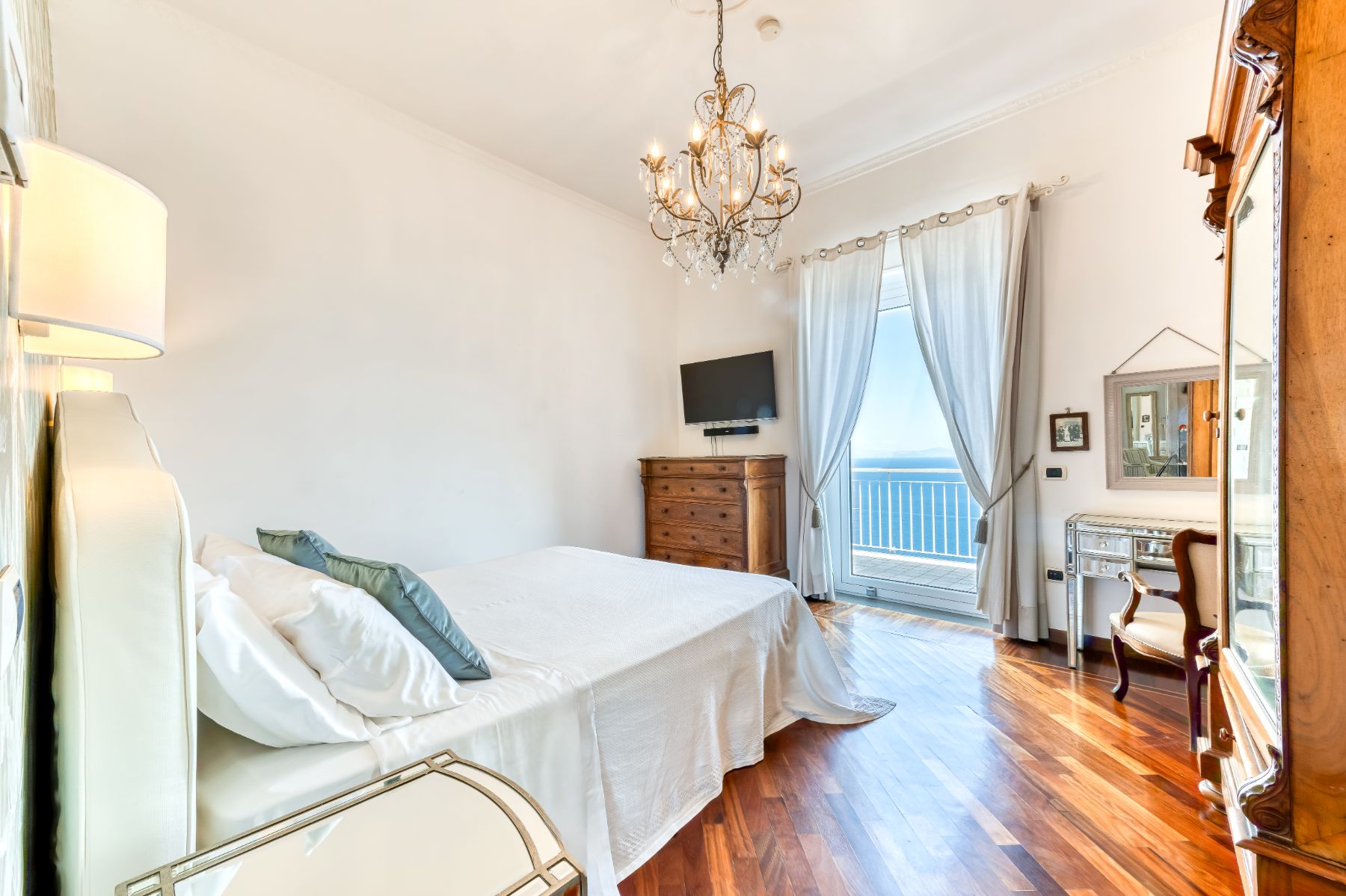 Bedroom with chest of drawers and television on the wall with views of the sea in Villa Li Galli in Amalfi