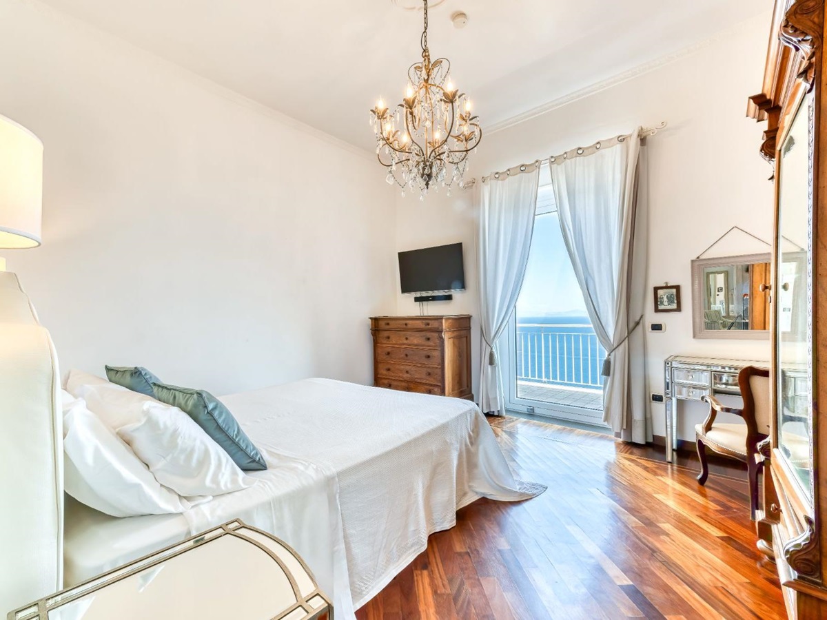 Bedroom with chest of drawers and television on the wall with views of the sea in Villa Li Galli in Amalfi