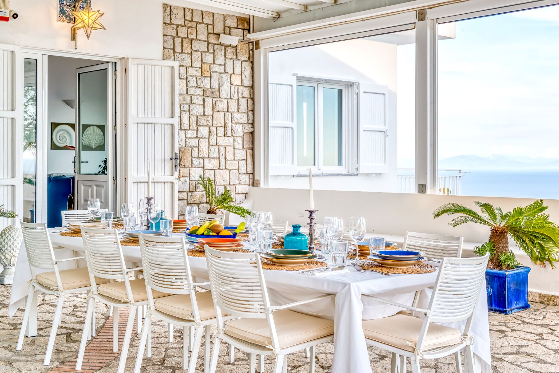 View of outdoor dining table on the stone patio with view of doors to the villa in Villa Li Galli in Amalfi