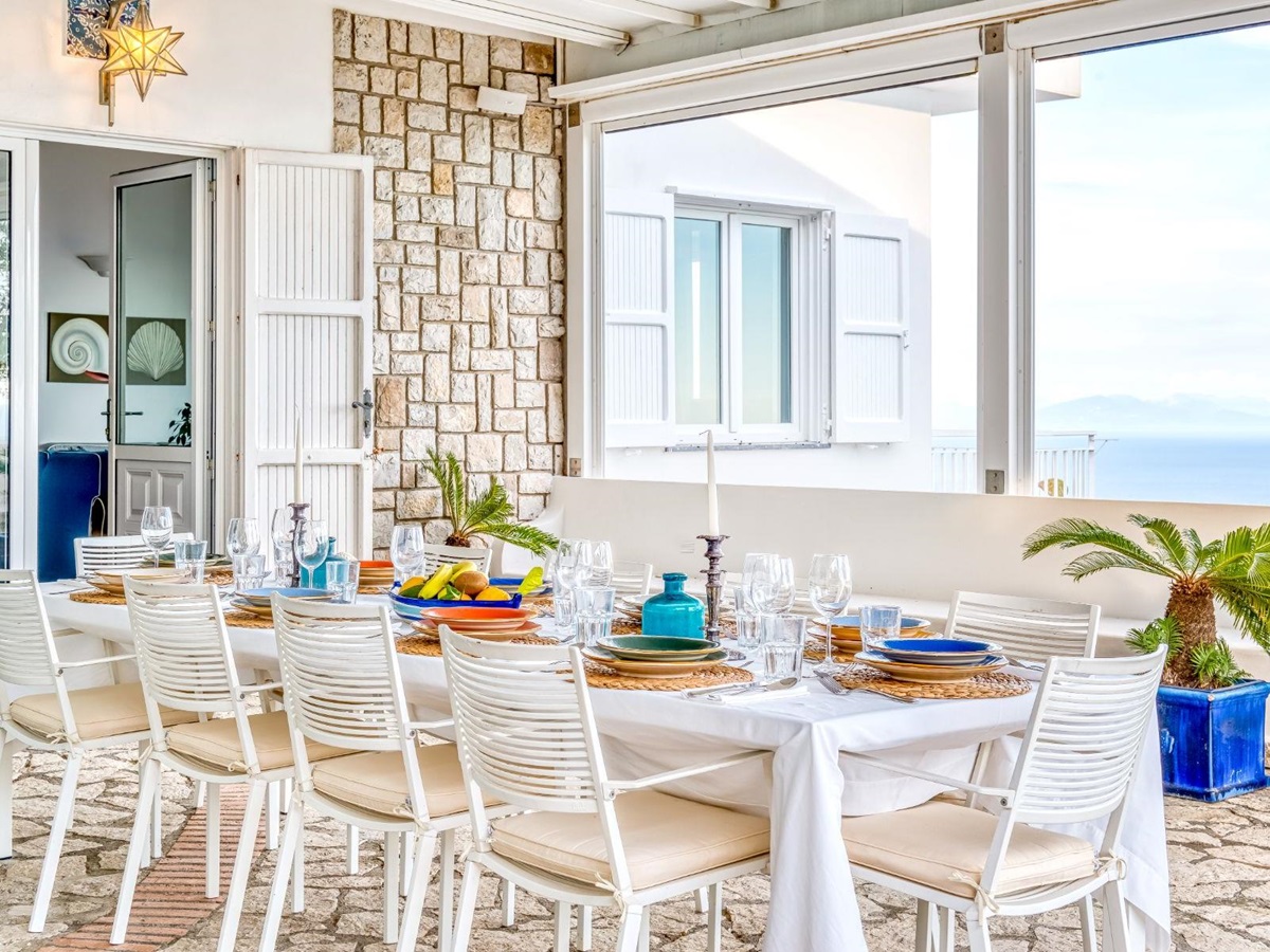View of outdoor dining table on the stone patio with view of doors to the villa in Villa Li Galli in Amalfi