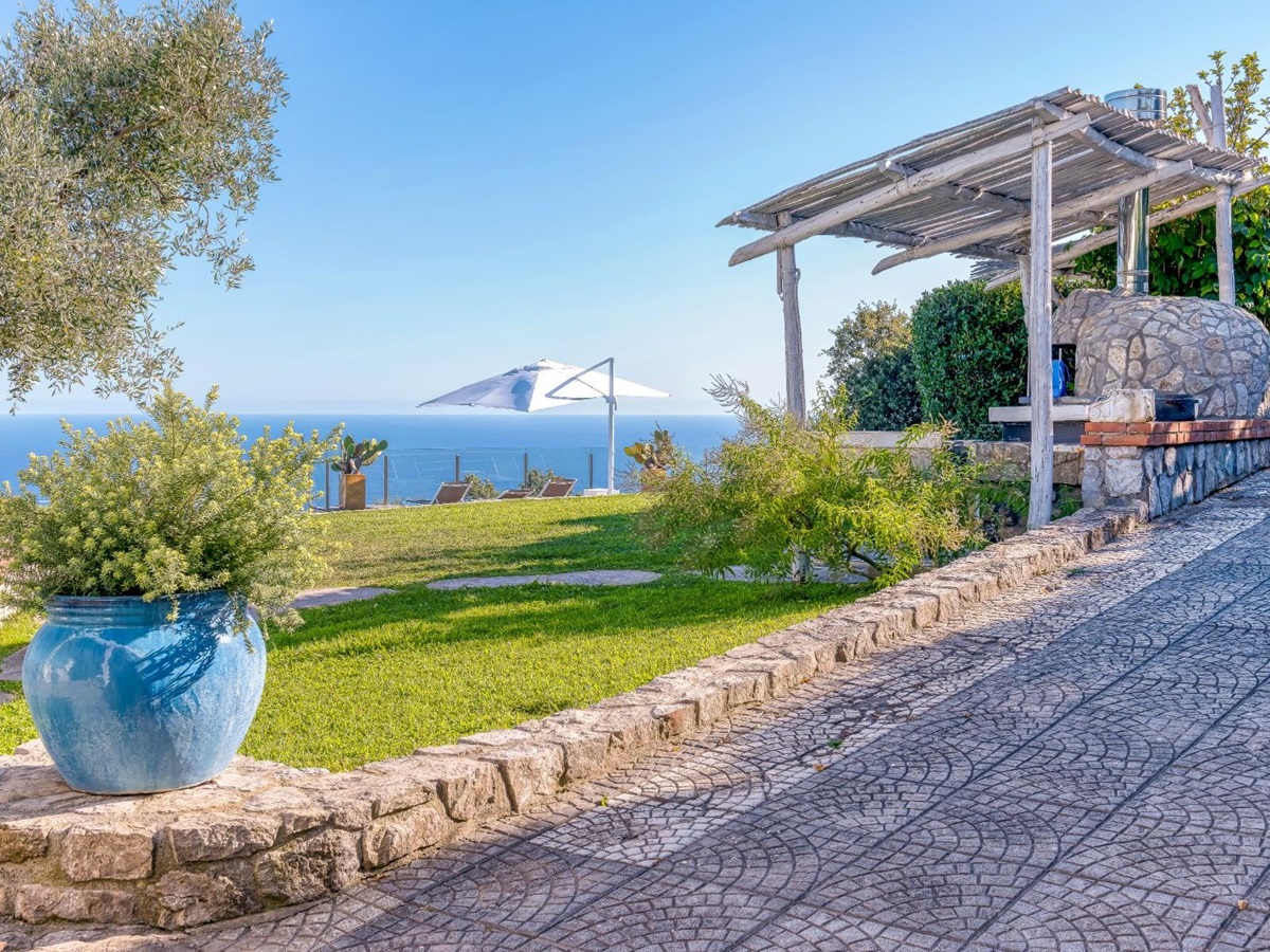 View from the patio of the grass area, with the pool terrace and sea view in the background at Villa Li Galli in Amalfi