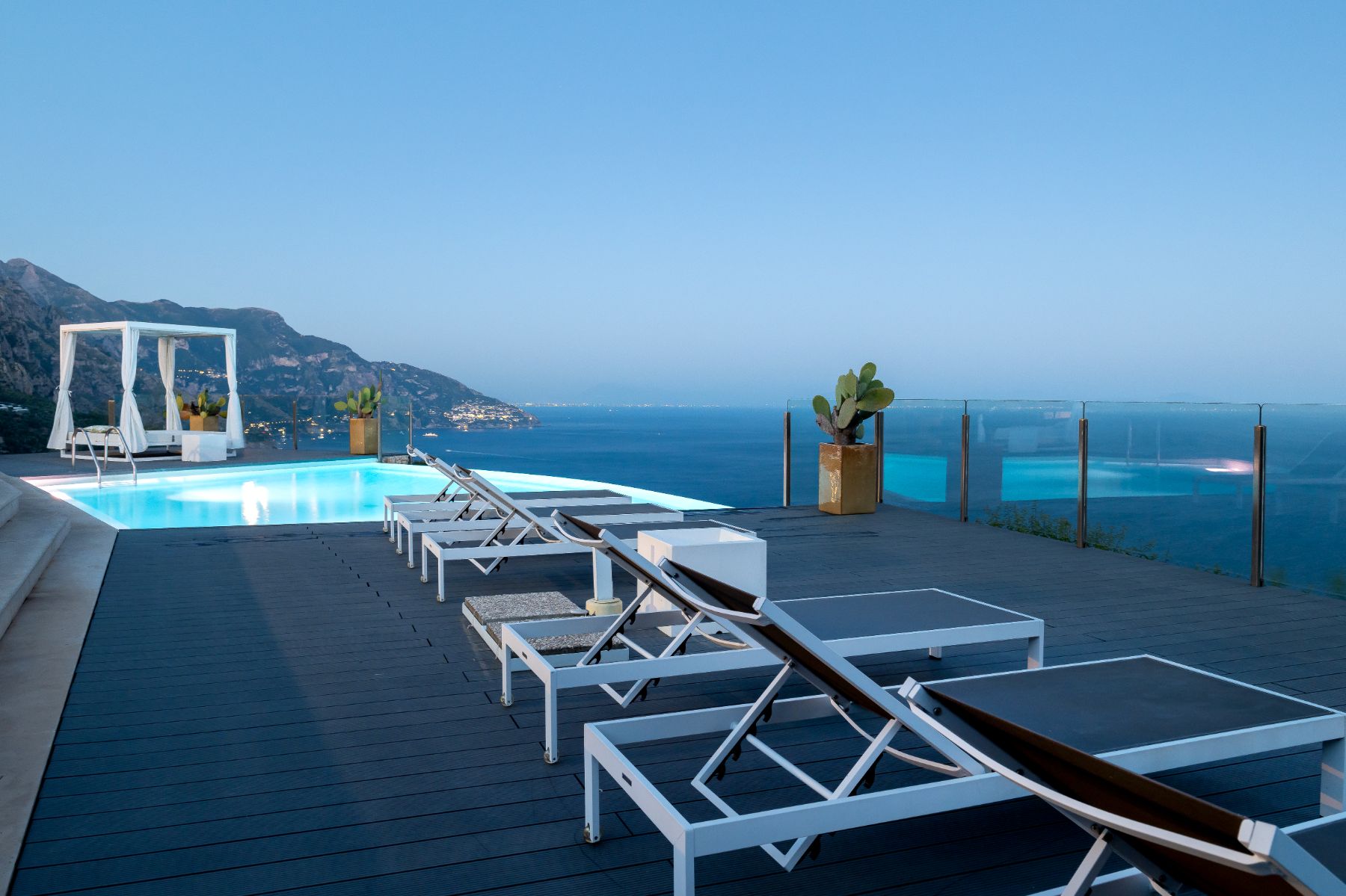 View of the terrace in the evening, with deck chairs and the infinity pool at Villa Li Galli in Amalfi