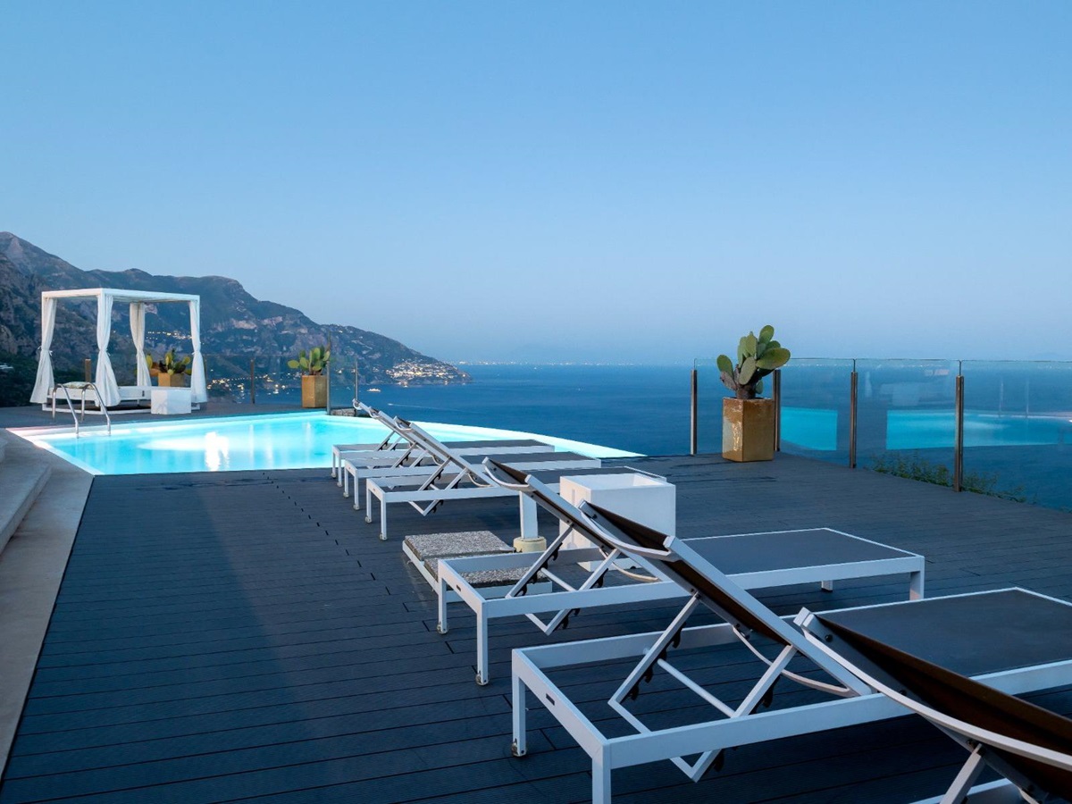 View of the terrace in the evening, with deck chairs and the infinity pool at Villa Li Galli in Amalfi