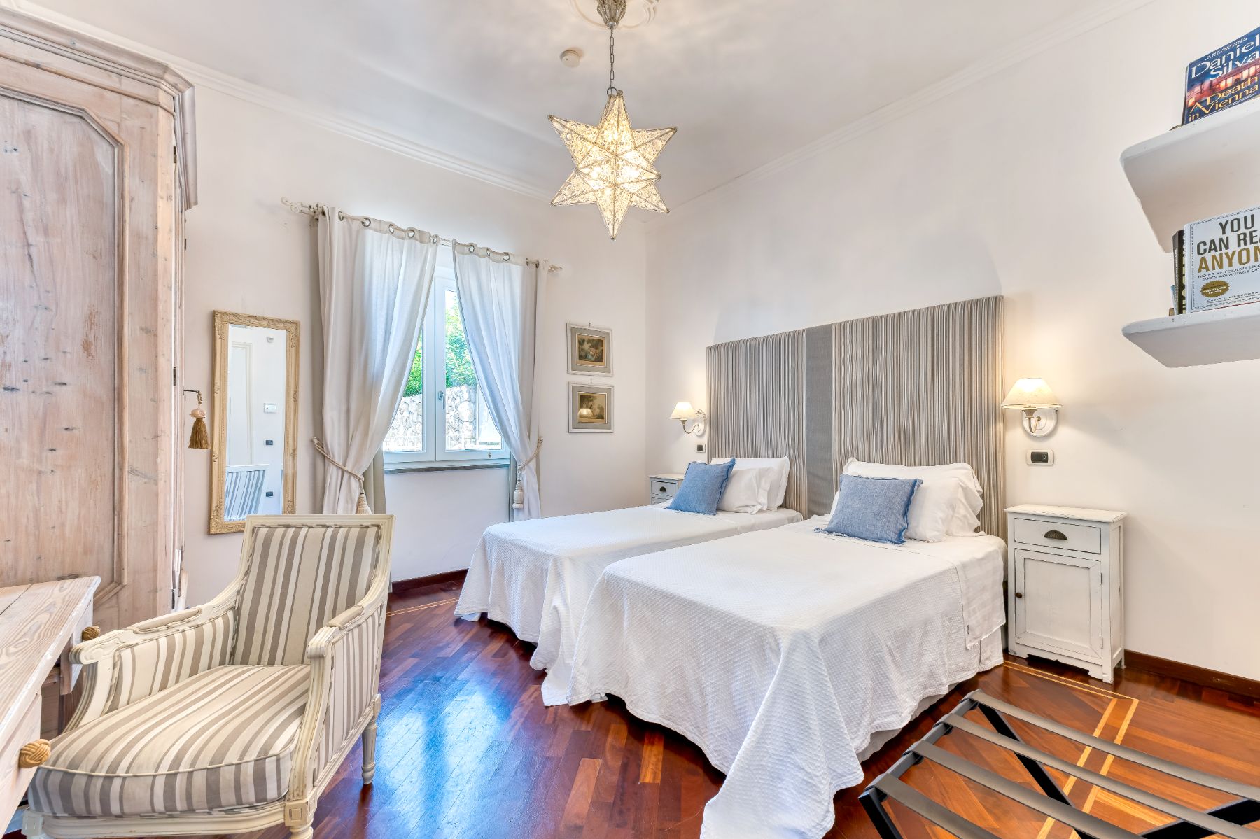 Twin bedroom with large wardrobe and chair at Villa Li Galli in Amalfi