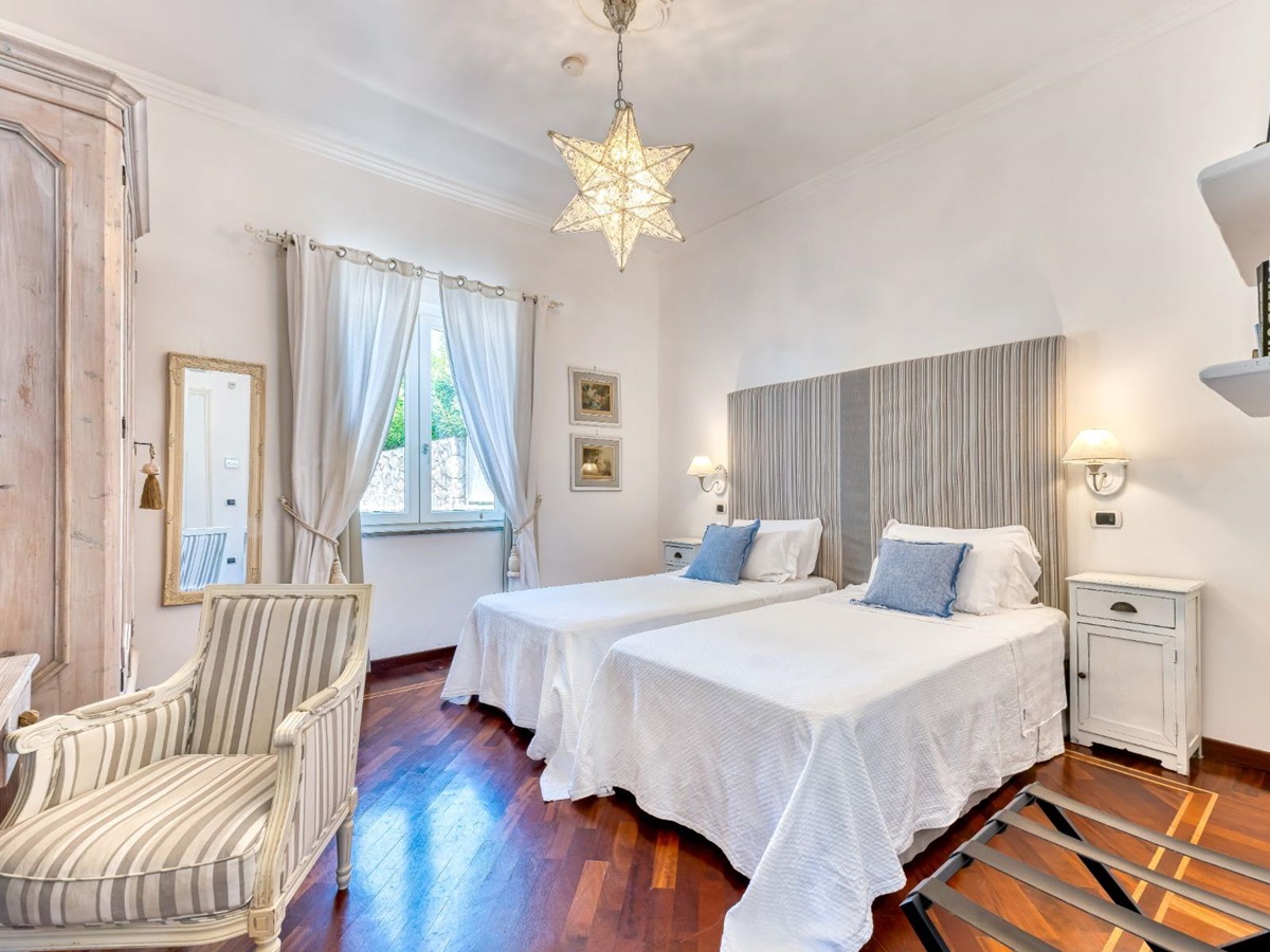 Twin bedroom with large wardrobe and chair at Villa Li Galli in Amalfi