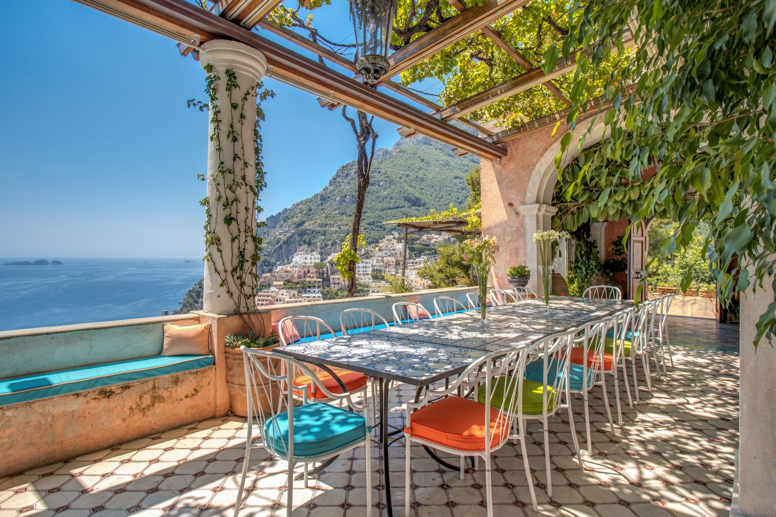 Outdoor dining table set for lunch under a lush green pergola