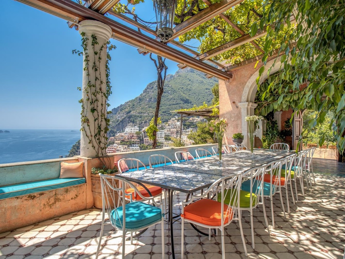Outdoor dining table set for lunch under a lush green pergola