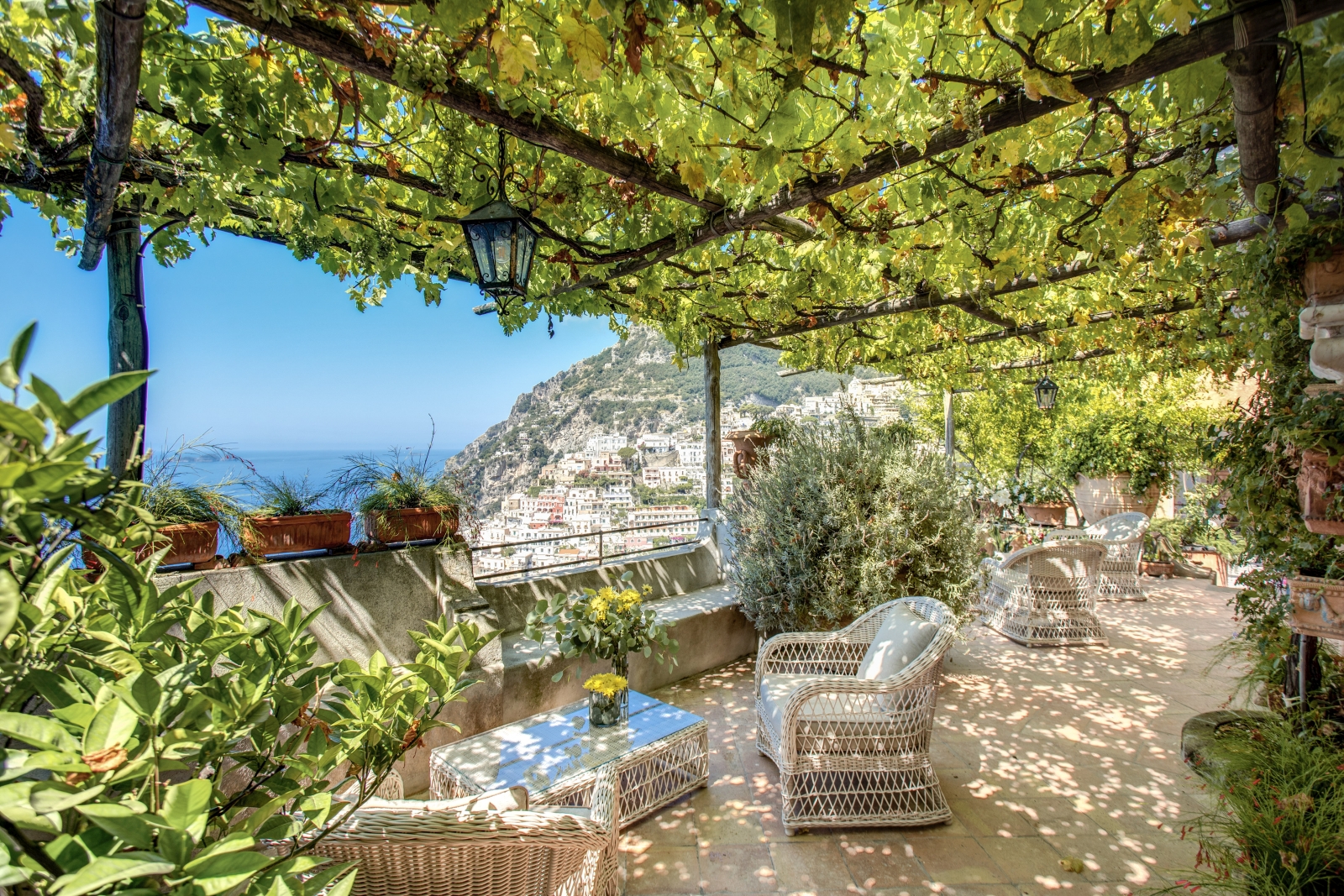 A set of comortable outdoor chairs on a tiled terrace with view of Amalfi