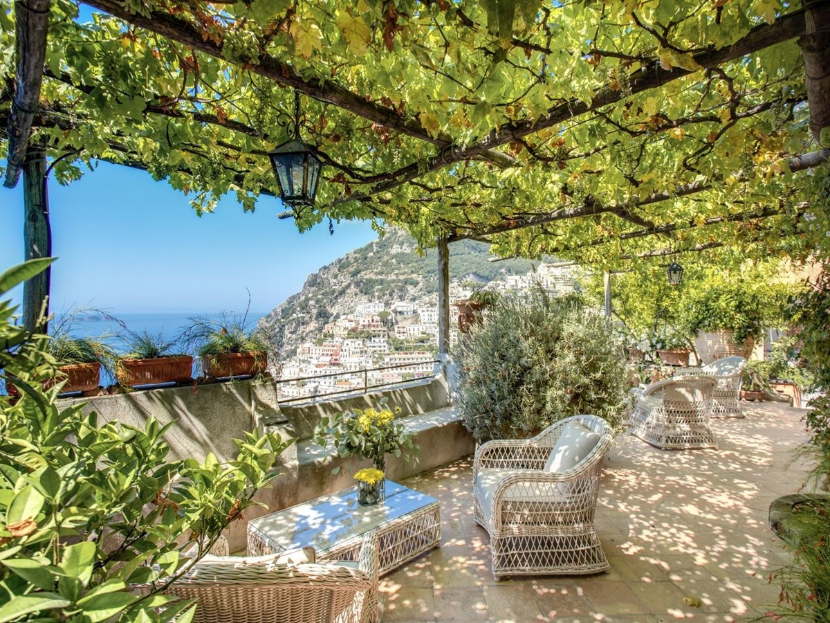 A set of comortable outdoor chairs on a tiled terrace with view of Amalfi