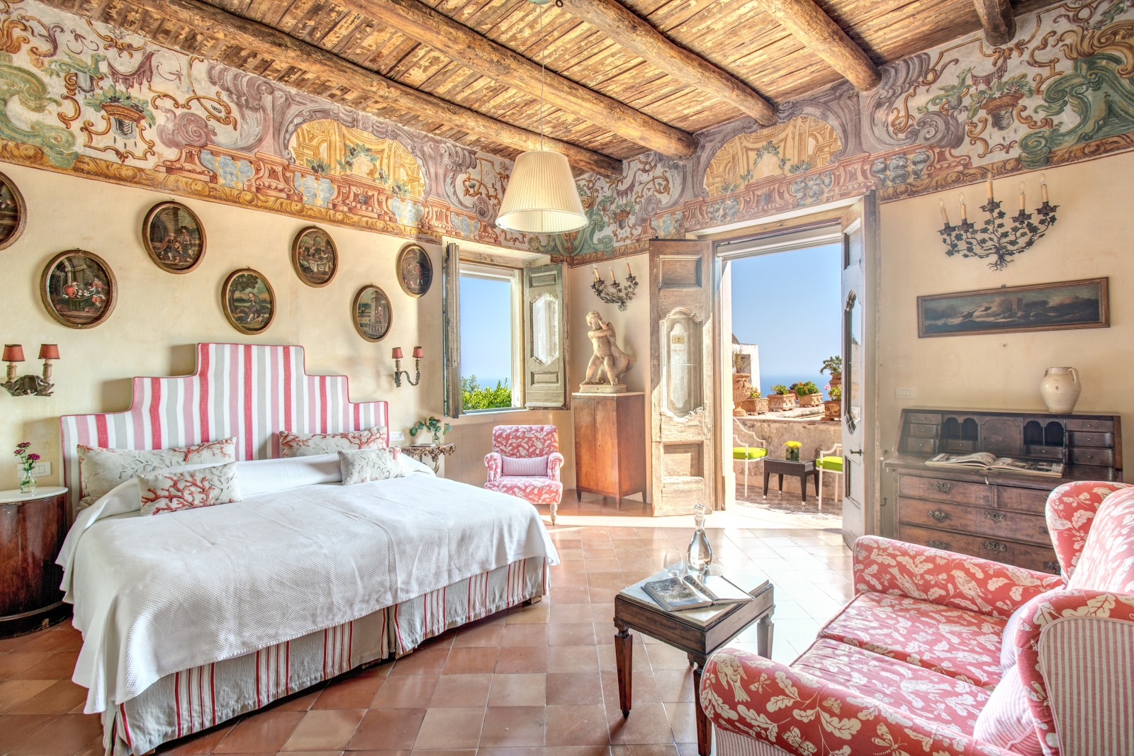 Twin bedroom with warm tones and view towards the sea from a balcony