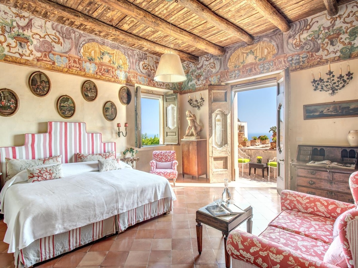 Twin bedroom with warm tones and view towards the sea from a balcony