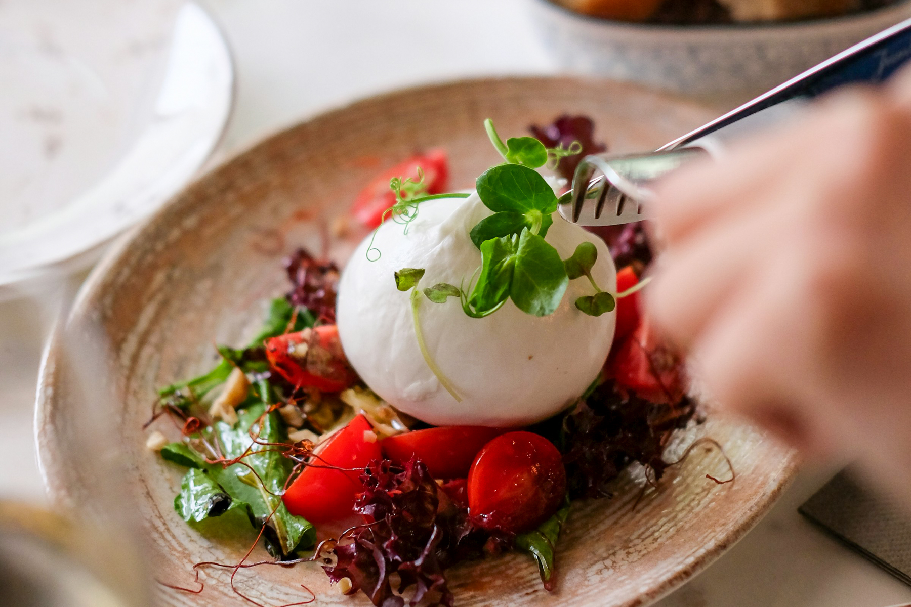 Burrata being cut open on a plate