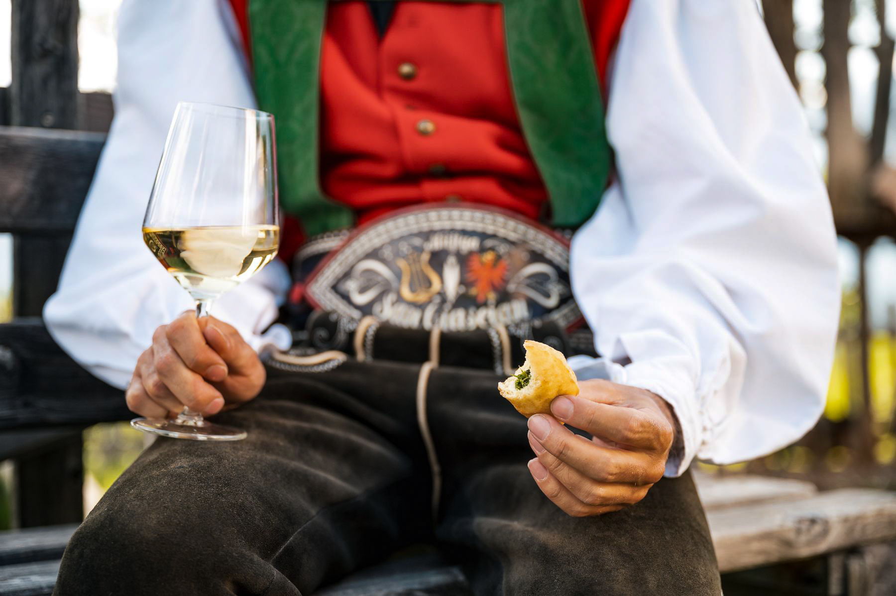 A man in traditional dress eating food in the Dolomites