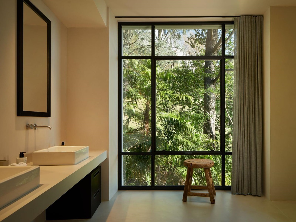 Bathroom at Breakwater Griante in Lake Como with view of a large window with a tree outside and view of basins