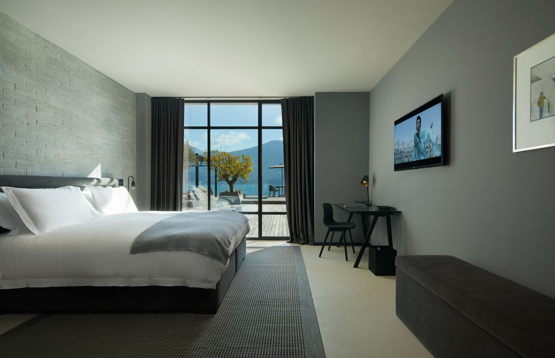 Bedroom in Breakwater Griante in Lake Como with a small black desk and chair and a large open window