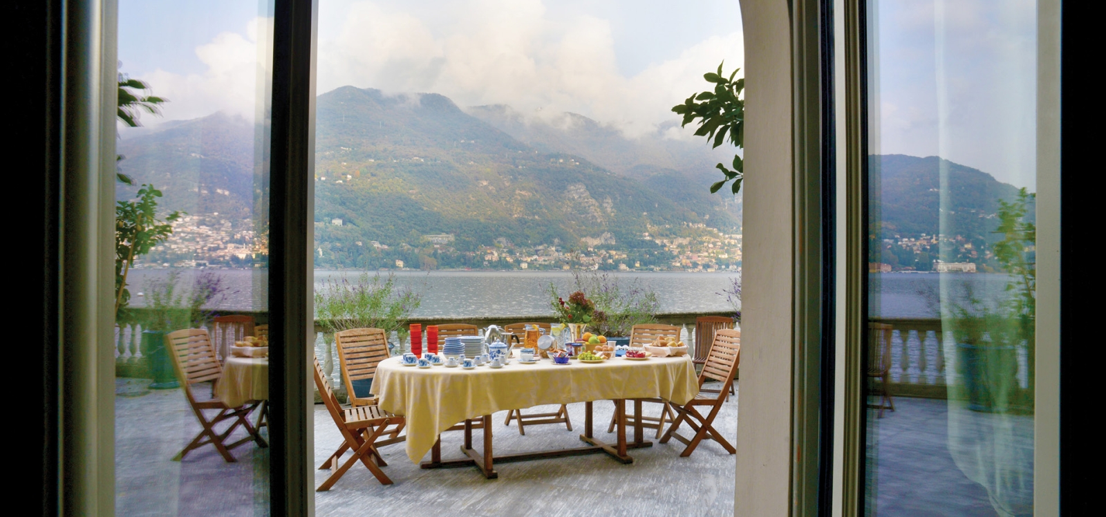 Balcony with dining table, plants and lake view at Ville del Lago on Lake Como, Italy