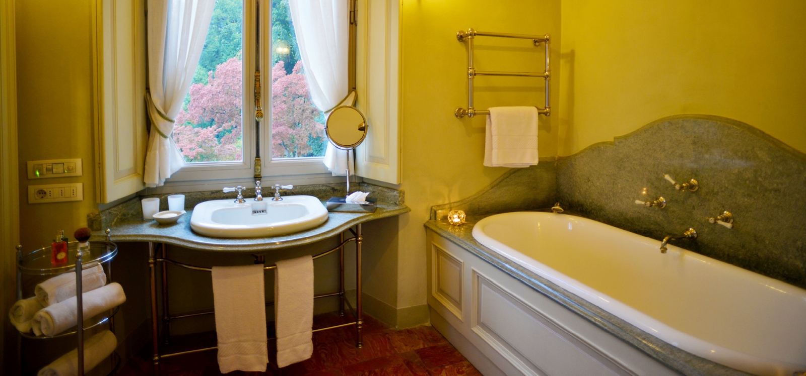 Bathroom with bath tub, sink, towel rail and window at Ville del Lago on Lake Como, Italy