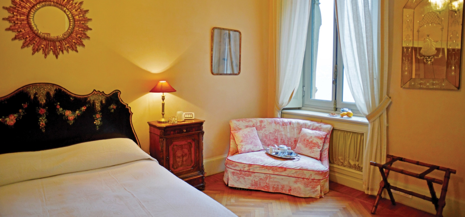Bedroom with double bed, armchair, bedside cabinet, lamp, mirror and window at Ville del Lago on Lake Como, Italy