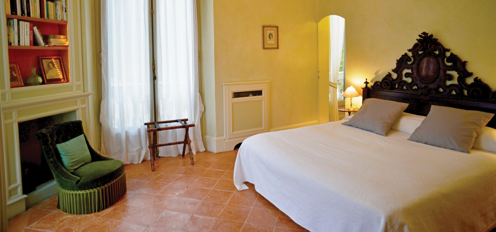 Bedroom with double bed, armchair, fireplace, bookshelves and balcony at Ville del Lago on Lake Como, Italy