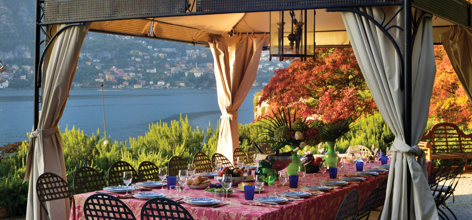 Outdoor dining area with marquee, dining table, chairs and view of lake at Ville del Lago on Lake Como, Italy