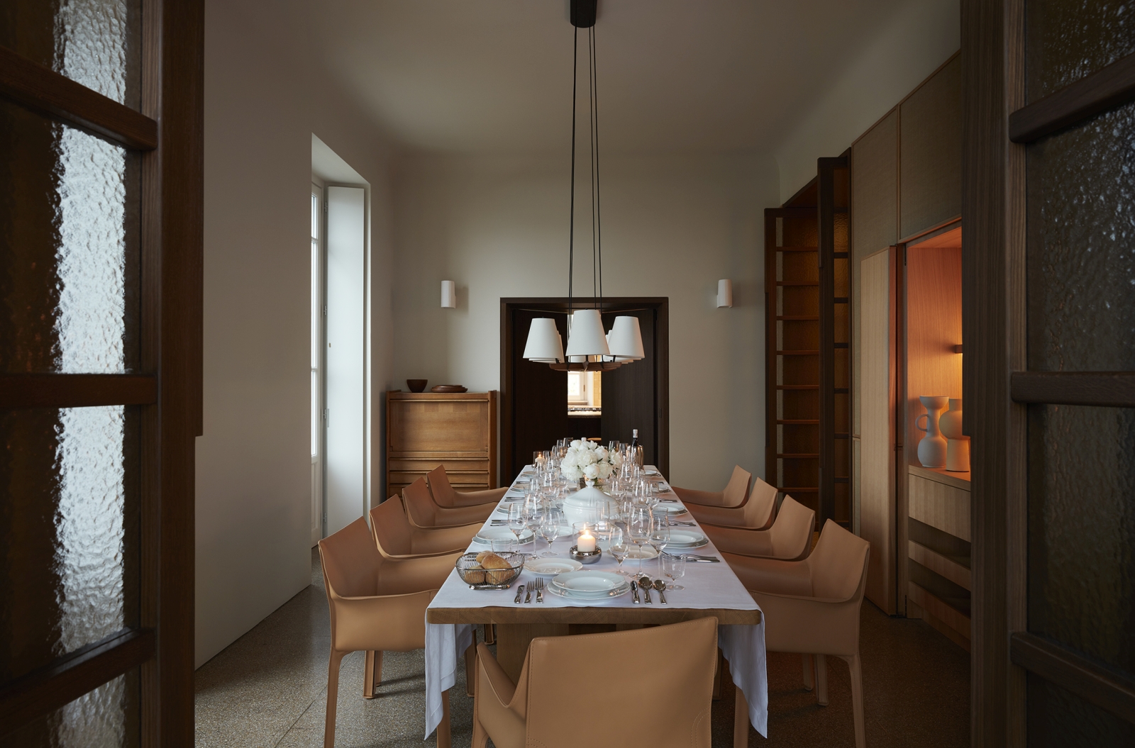 Formal dining room with long dining table, 10 chairs and overhanging lights at Villa della Vetta on Lake Como in Italy