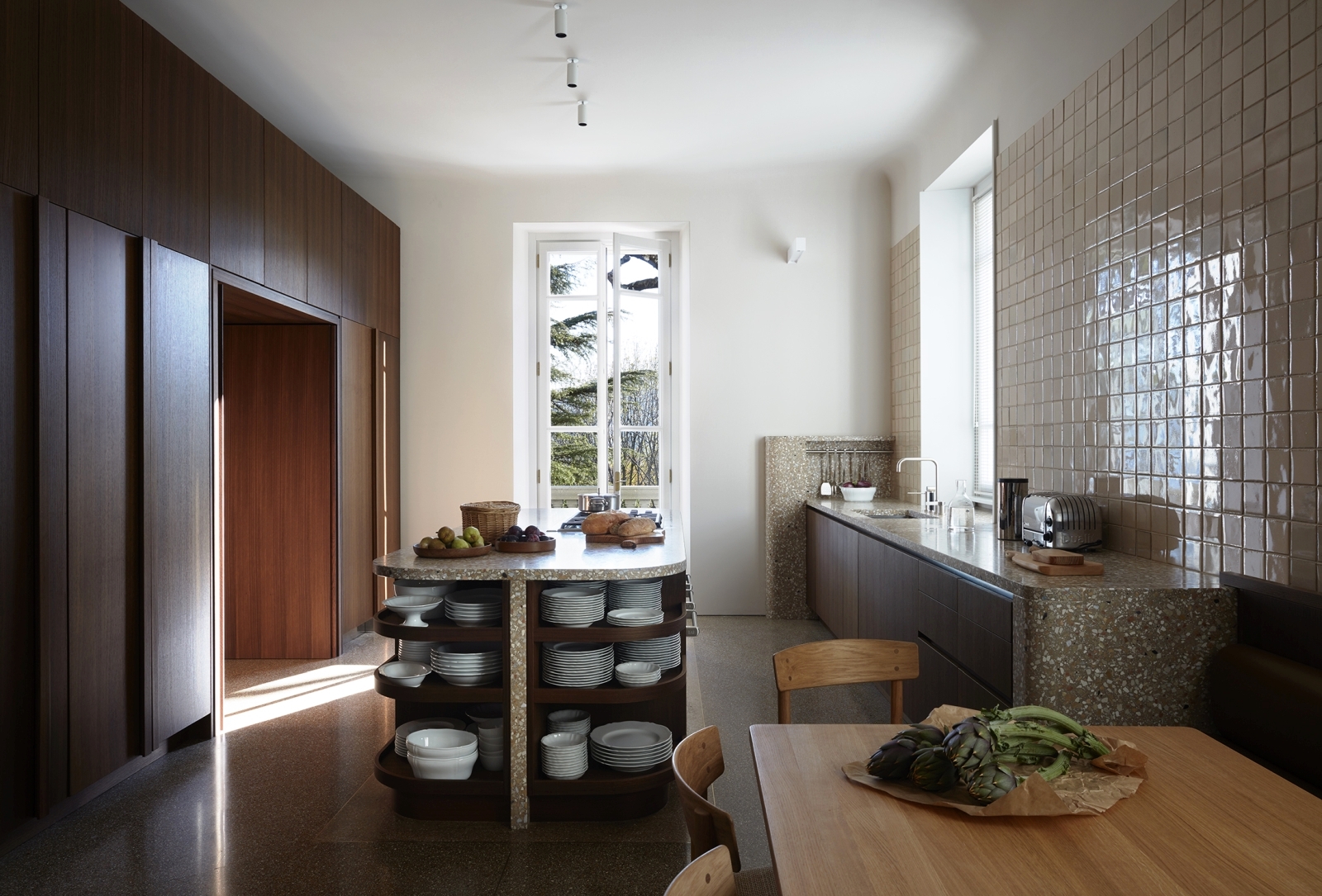 Kitchen with fresh food on table and island bar and tiled wall with windows at Villa della Vetta on Lake Como in Italy