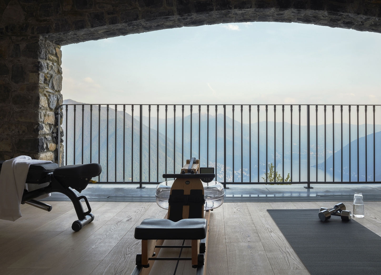 Balcony gym with equipment and view of lake and mountains behind black railings at Villa della Vetta on Lake Como in Italy