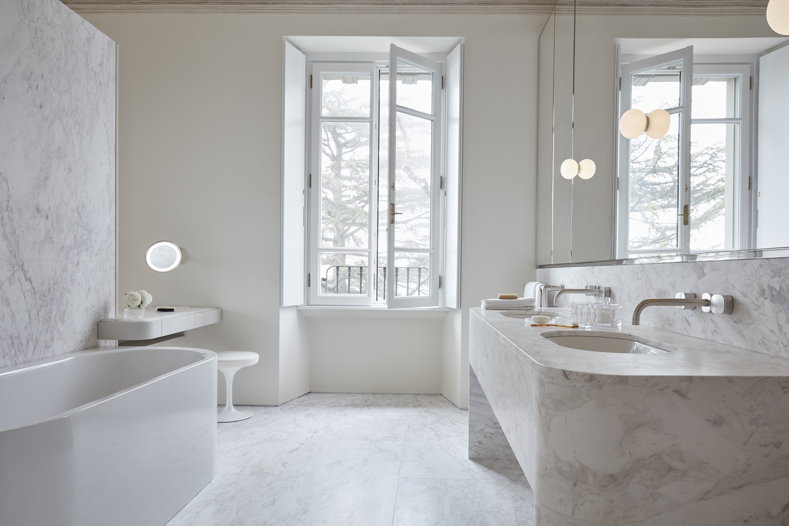 Master suite bathroom with white marble interior, bath, sinks, mirror and window at Villa della Vetta on Lake Como in Italy