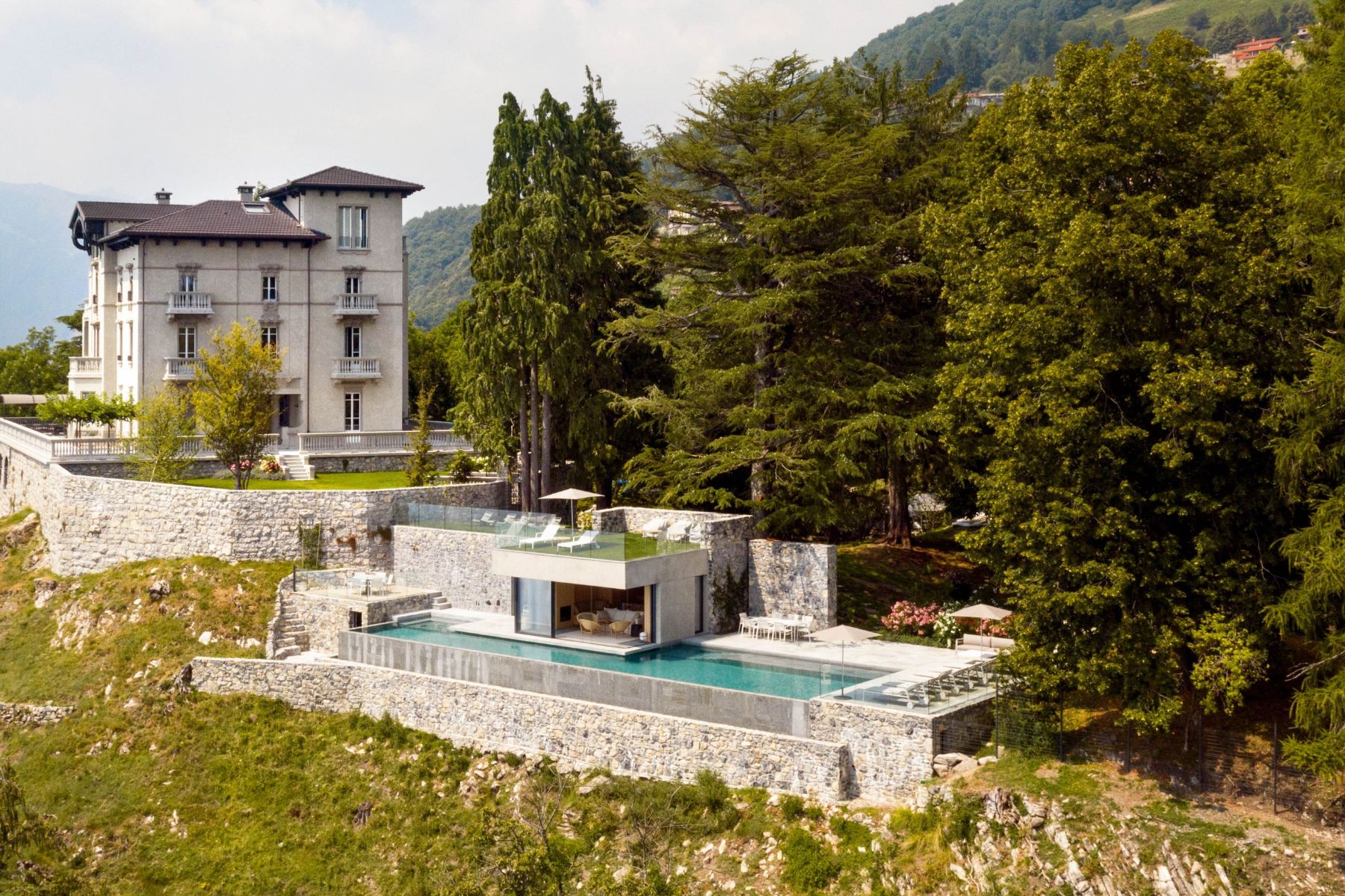 Drone view of the outdoor pool area surrounded by trees at Villa Della Vetta in Lake Como