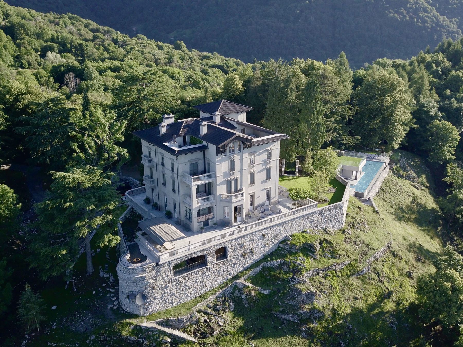 Drone view of Villa Della Vetta in Lake Como with view of the property and outdoor pool in the mountain