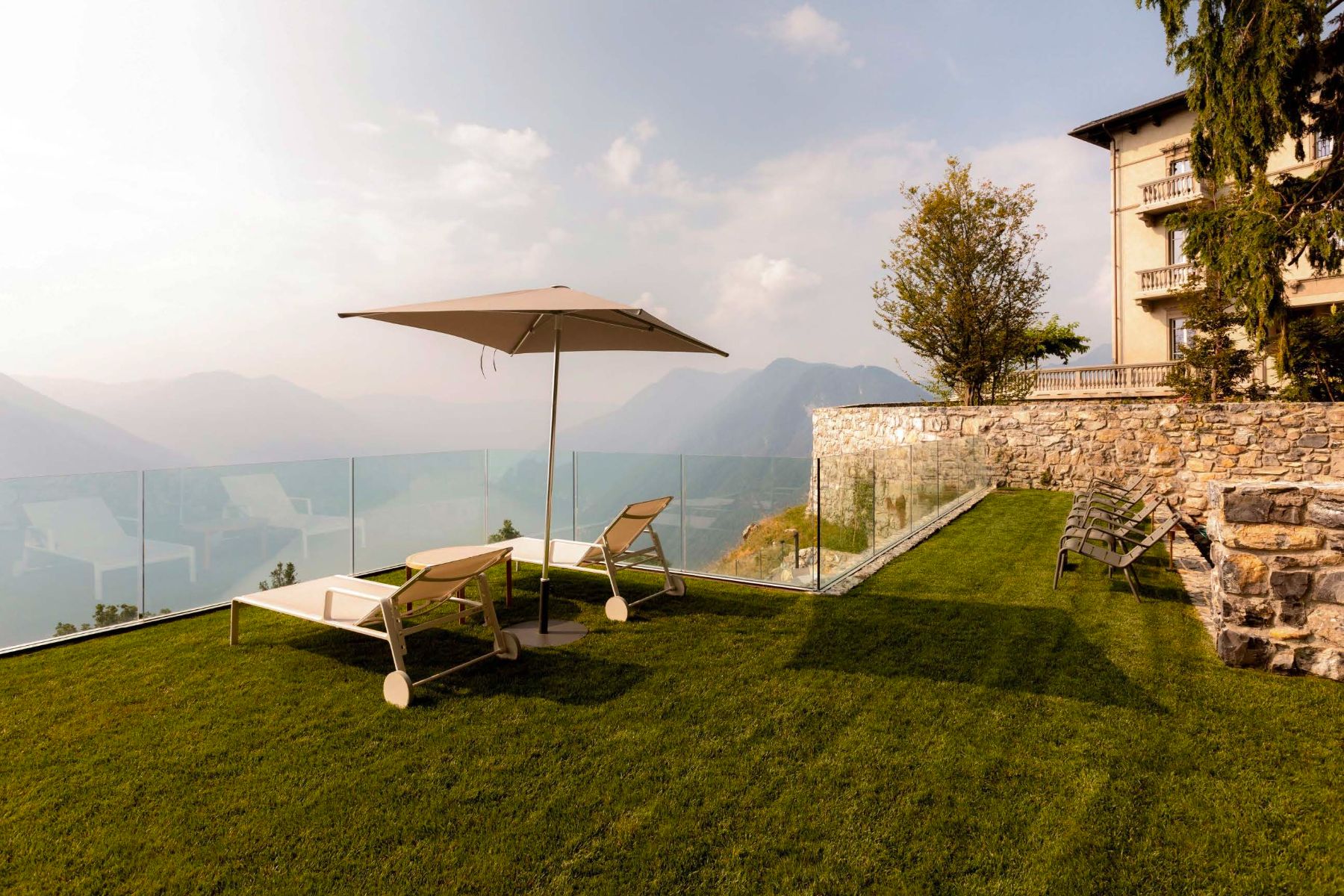 Grass area with sun loungers and an umbrella with views over Lake Como at Villa Della Vetta