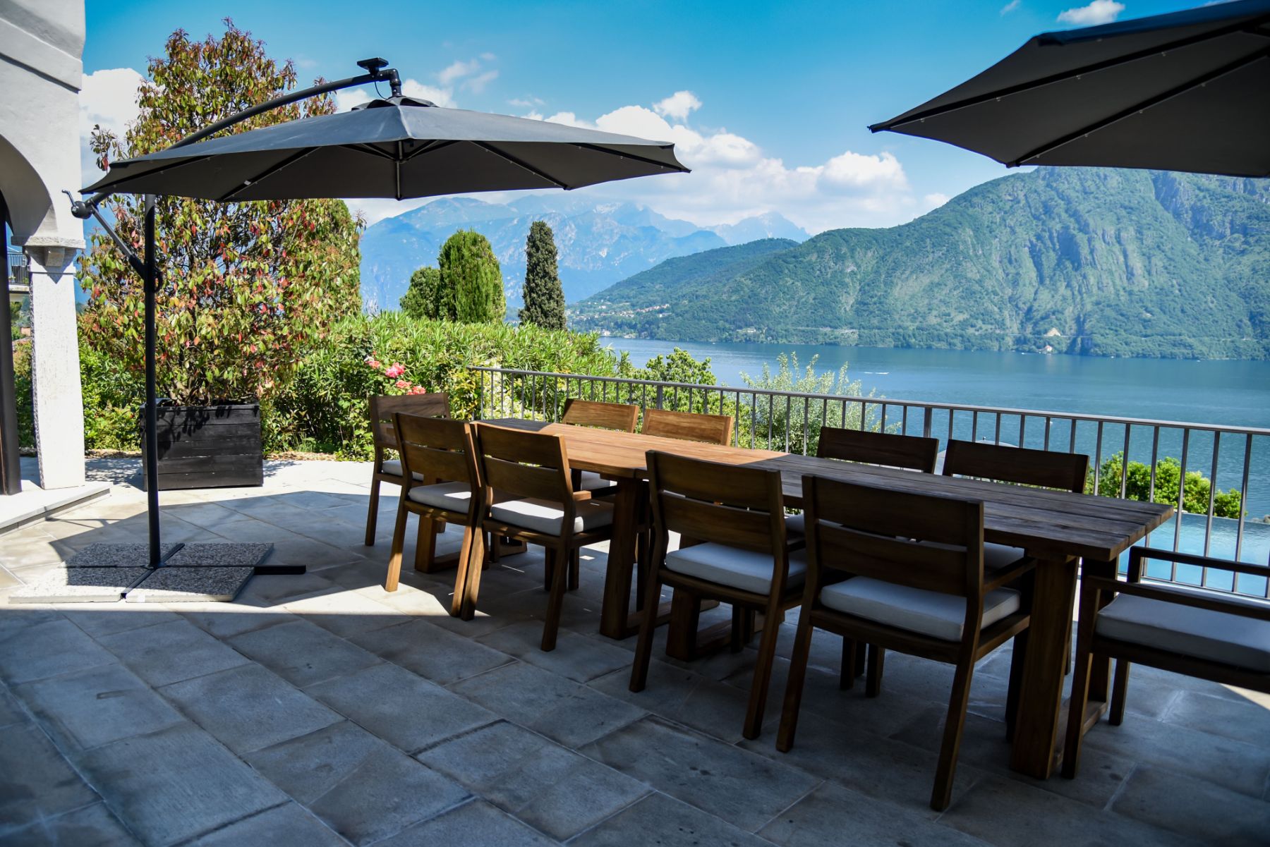 Outdoor dining table with parasols overlooking Lake Como at lucxury rental Villa Pola in the Italian Lakes, Italy