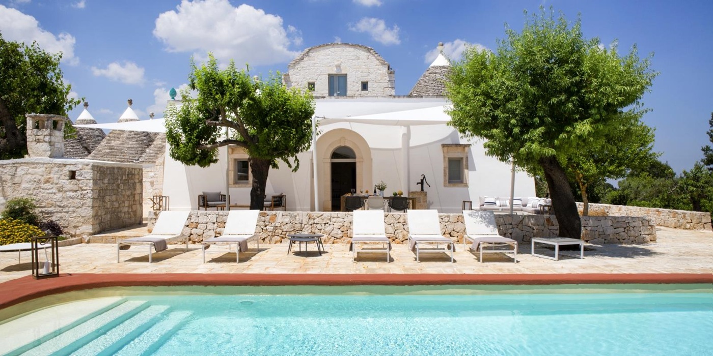 Pool and pool area with sun loungers, coffee table and trees at Masseria Bianco in Puglia, Italy