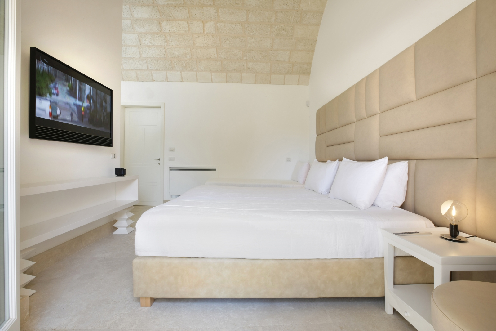 Bedroom with double bed, single bed, bedside table, lamp, TV and stone ceiling at Masseria dei Papi in Puglia, Italy