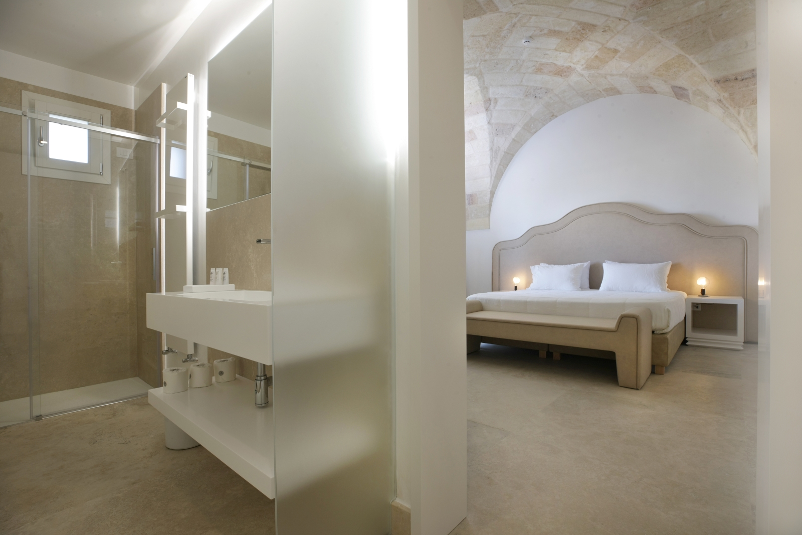 Bedroom with double bed, bedside table, lamp and ensuite with sink, shower and mirror at Masseria dei Papi in Puglia, Italy