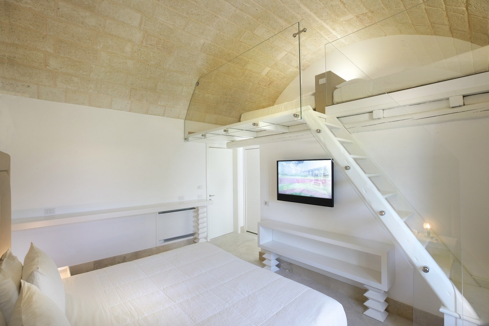 Family bedroom with double bed, TV and mezzanine floor at Masseria dei Papi in Puglia, Italy