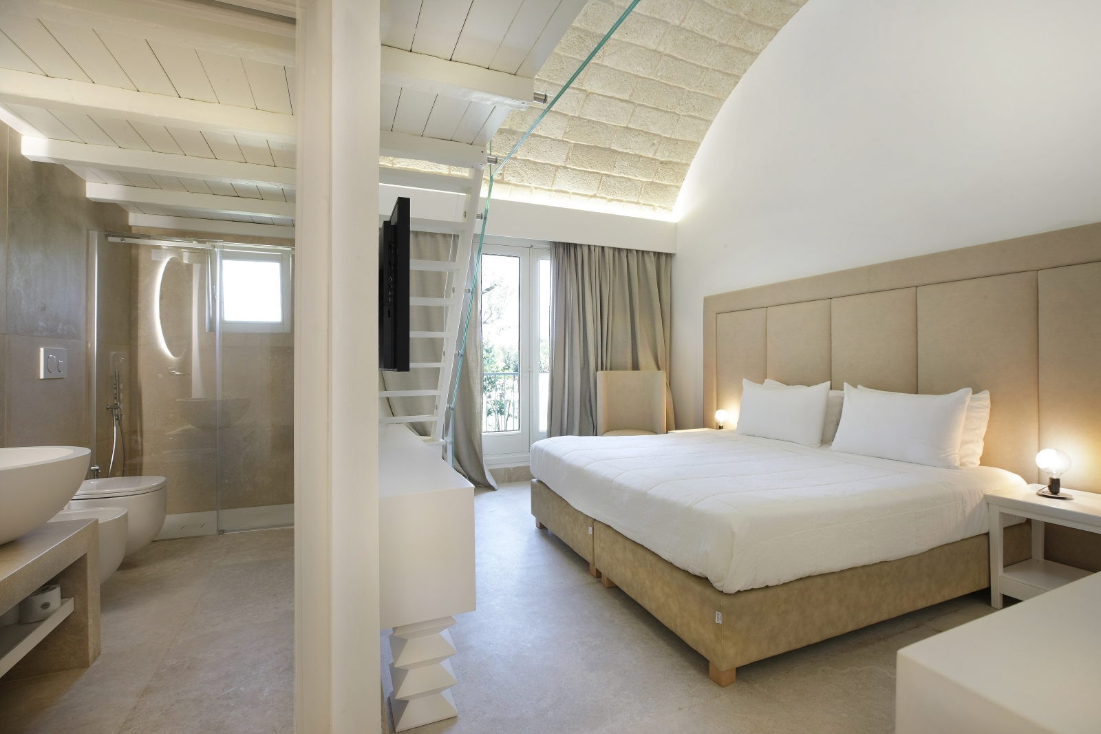 Bedroom with double bed, bedside table, armchair, ensuite bathroom and mezzanine at Masseria dei Papi in Puglia, Italy