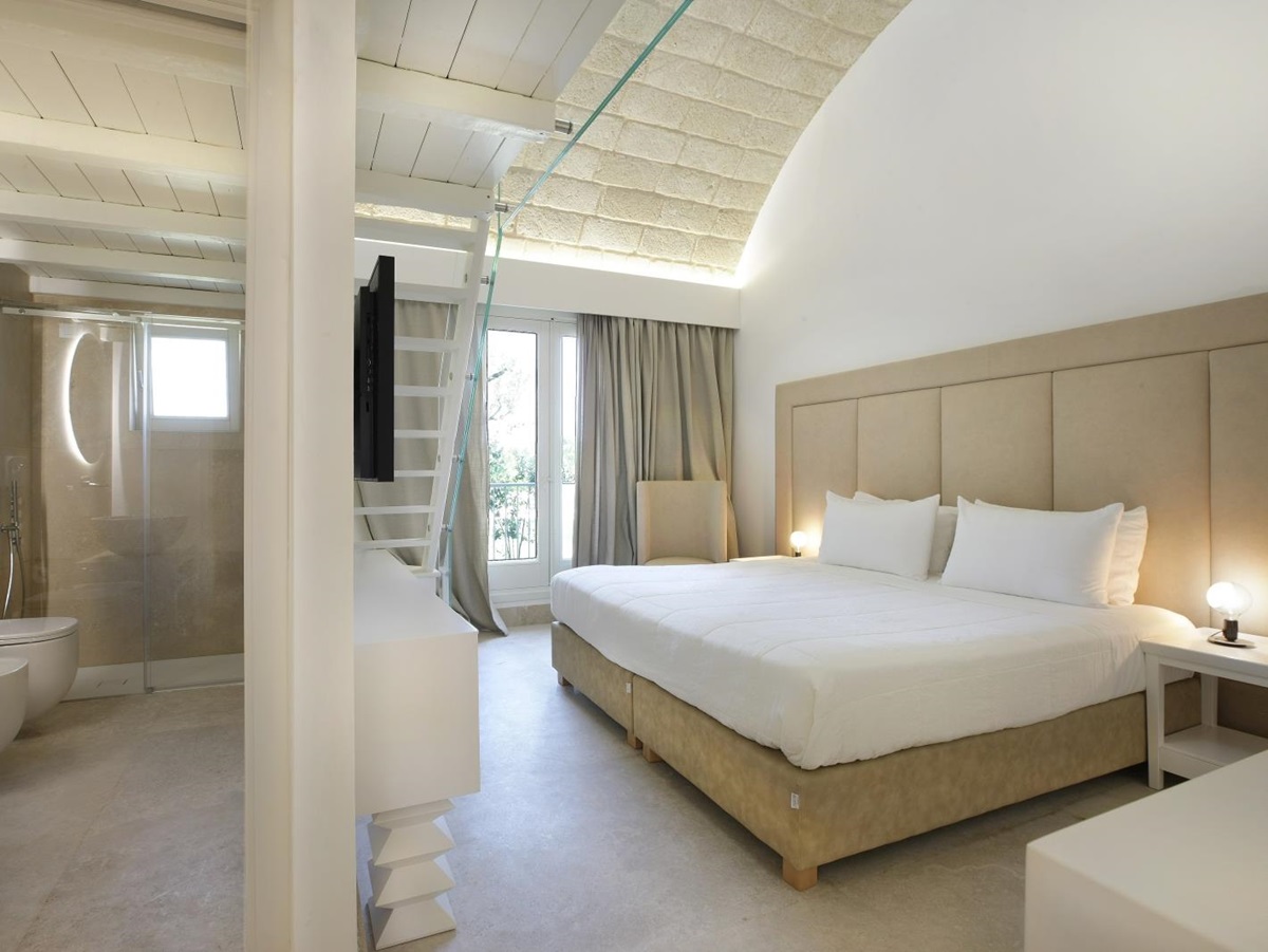 Bedroom with double bed, bedside table, armchair, ensuite bathroom and mezzanine at Masseria dei Papi in Puglia, Italy