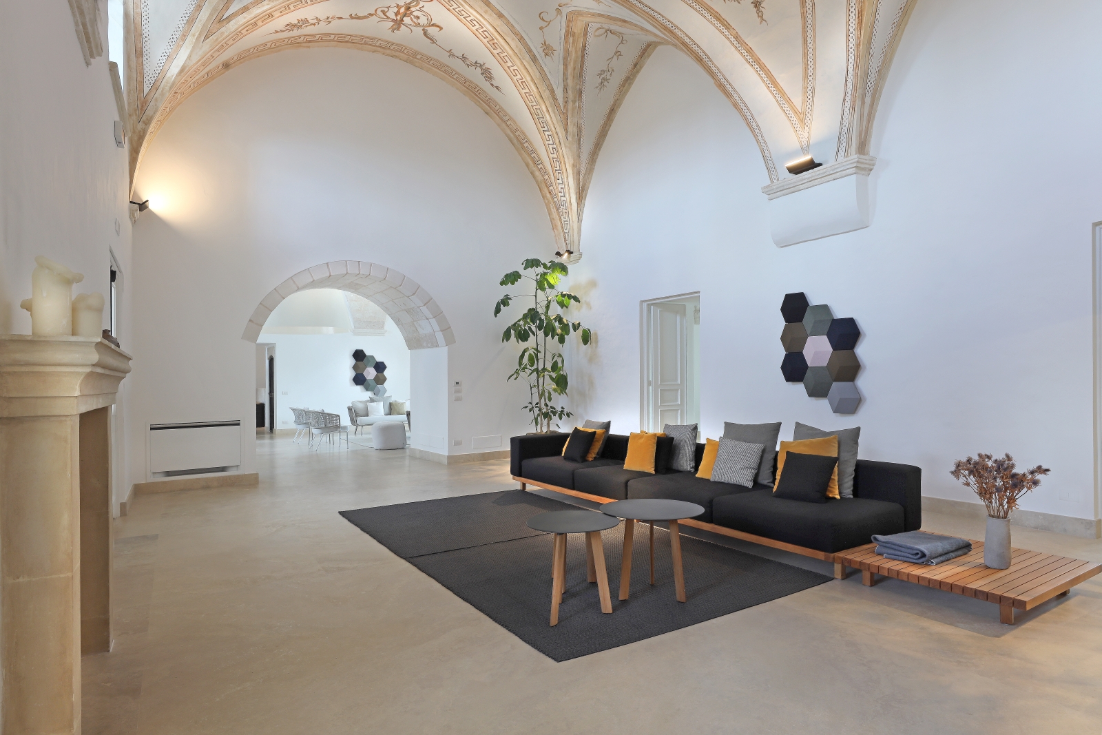 Living room with long sofa, tables, fireplace and vaulted ceiling at Masseria dei Papi in Puglia, Italy