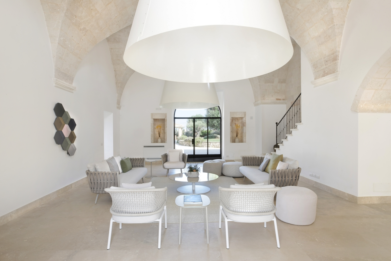 Living room with armchairs, sofas, stools, tables, vaulted ceilings and French doors at Masseria dei Papi in Puglia, Italy
