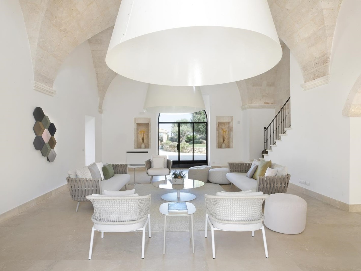 Living room with armchairs, sofas, stools, tables, vaulted ceilings and French doors at Masseria dei Papi in Puglia, Italy
