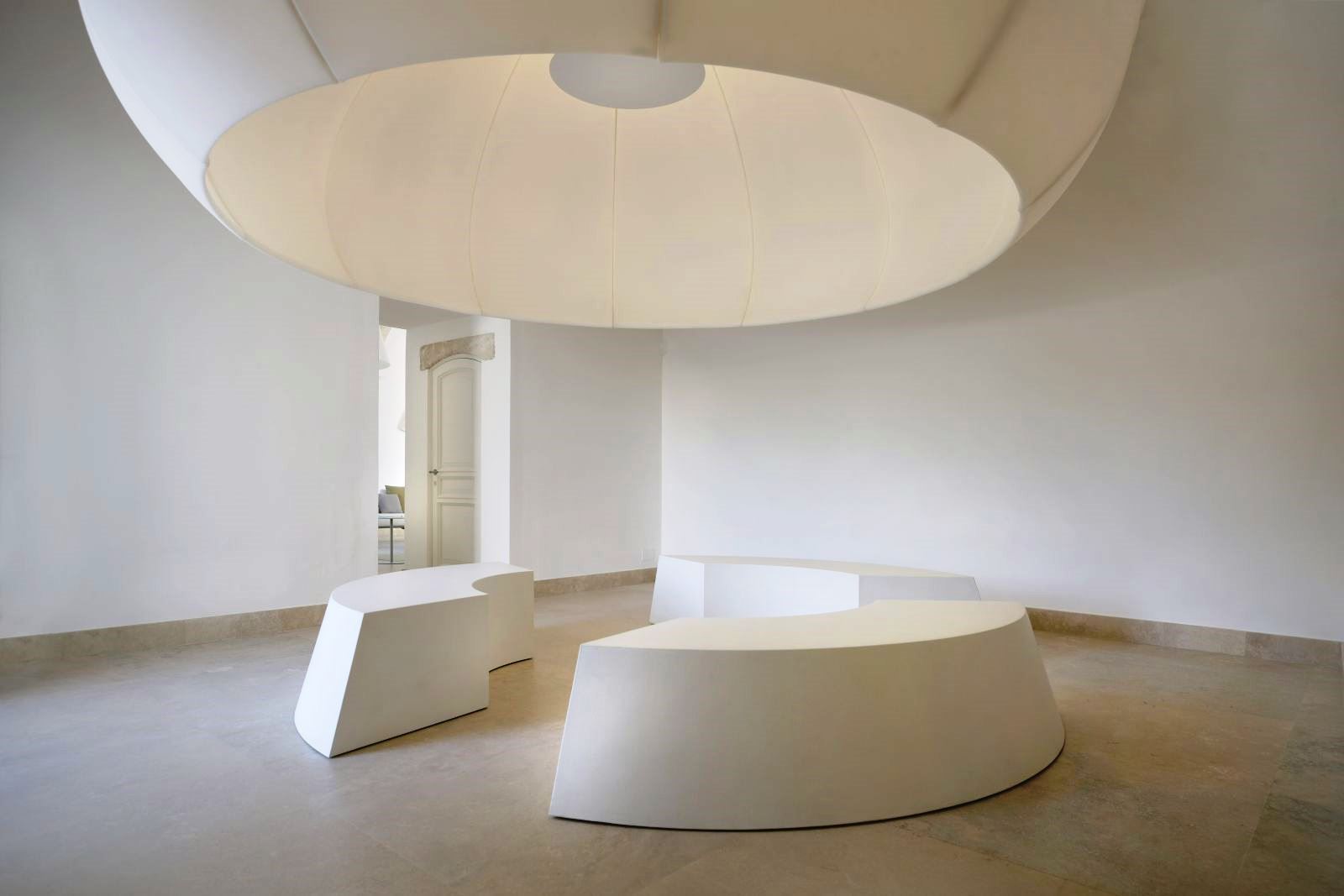 Big white Eden masterpiece XXXL lamp, above 3 white curved seats at villa masseria dei papi in Puglia, Italy